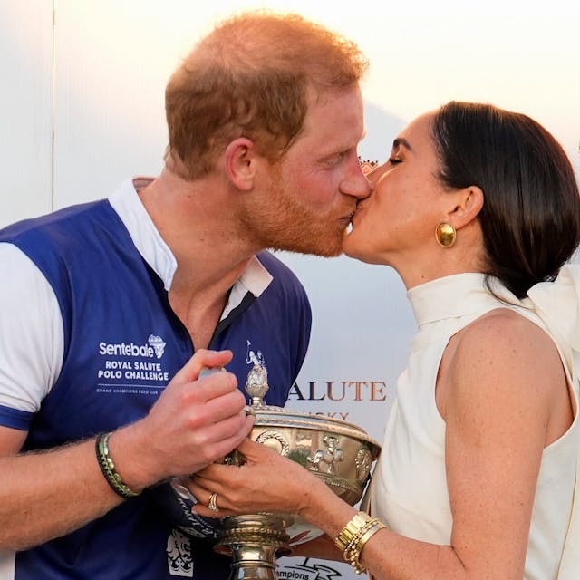 Der britische Prinz Harry (l), und seine Frau Meghan küssen sich, während sie seinem Polo-Team die Trophäe für den Sieg bei der Royal Salute Polo Challenge to Benefit Sentebale überreicht.