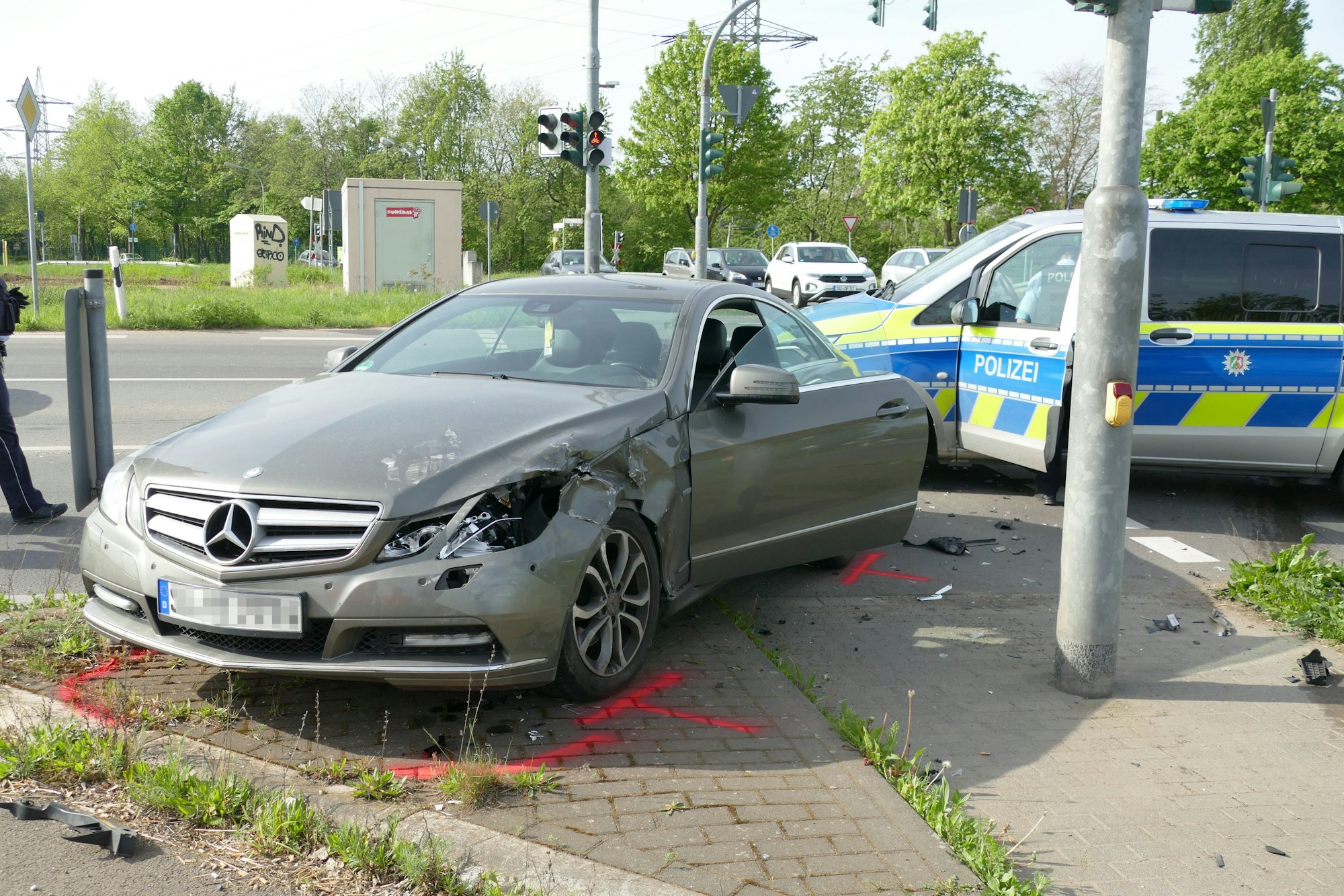 Ein kaputter Mercedes steht auf einer Verkehrsinsel.