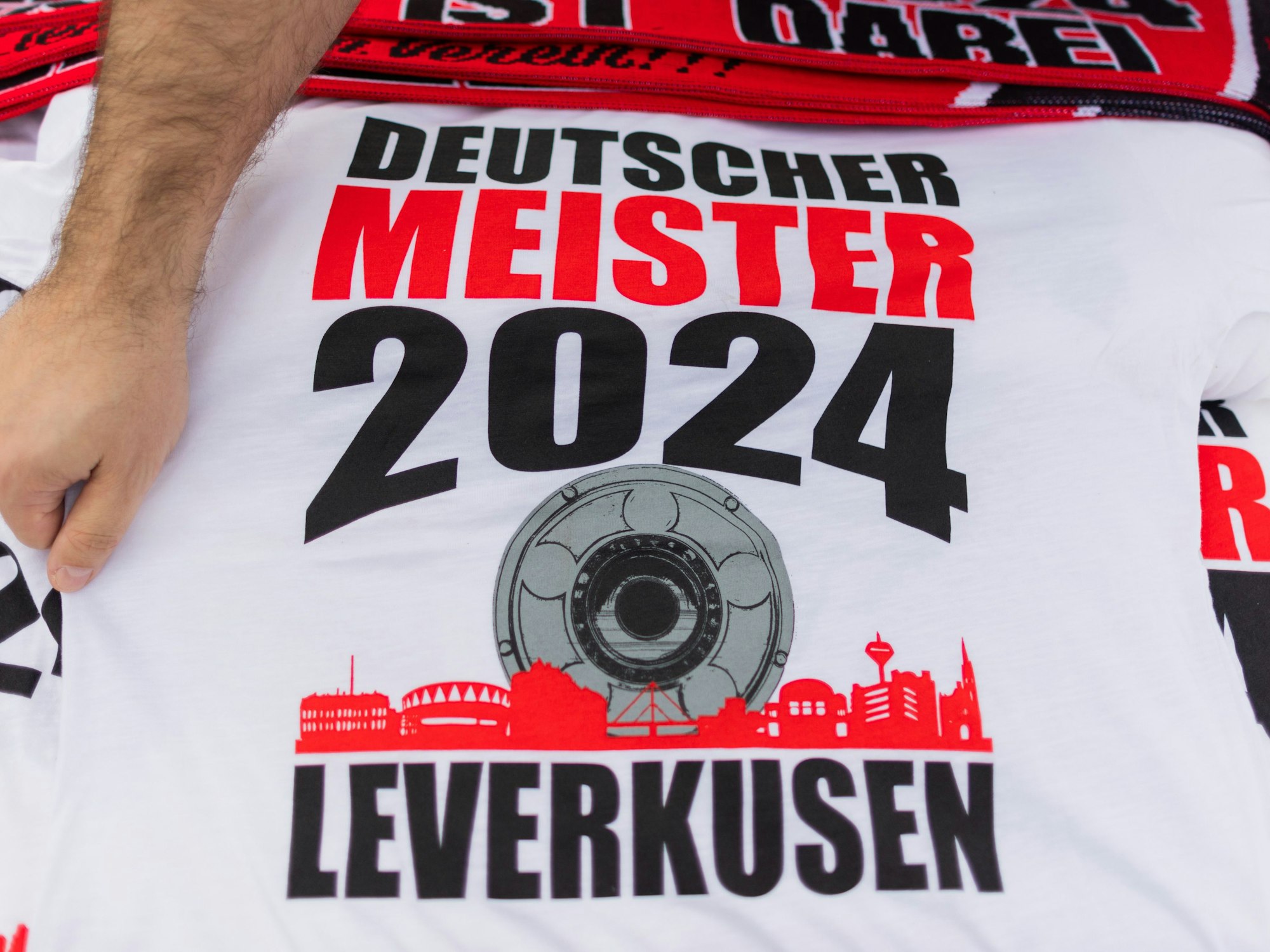 Ein Händler bietet T-Shirts mit der Aufschrift ·Deutscher Meister 2024 - Leverkusen· an.