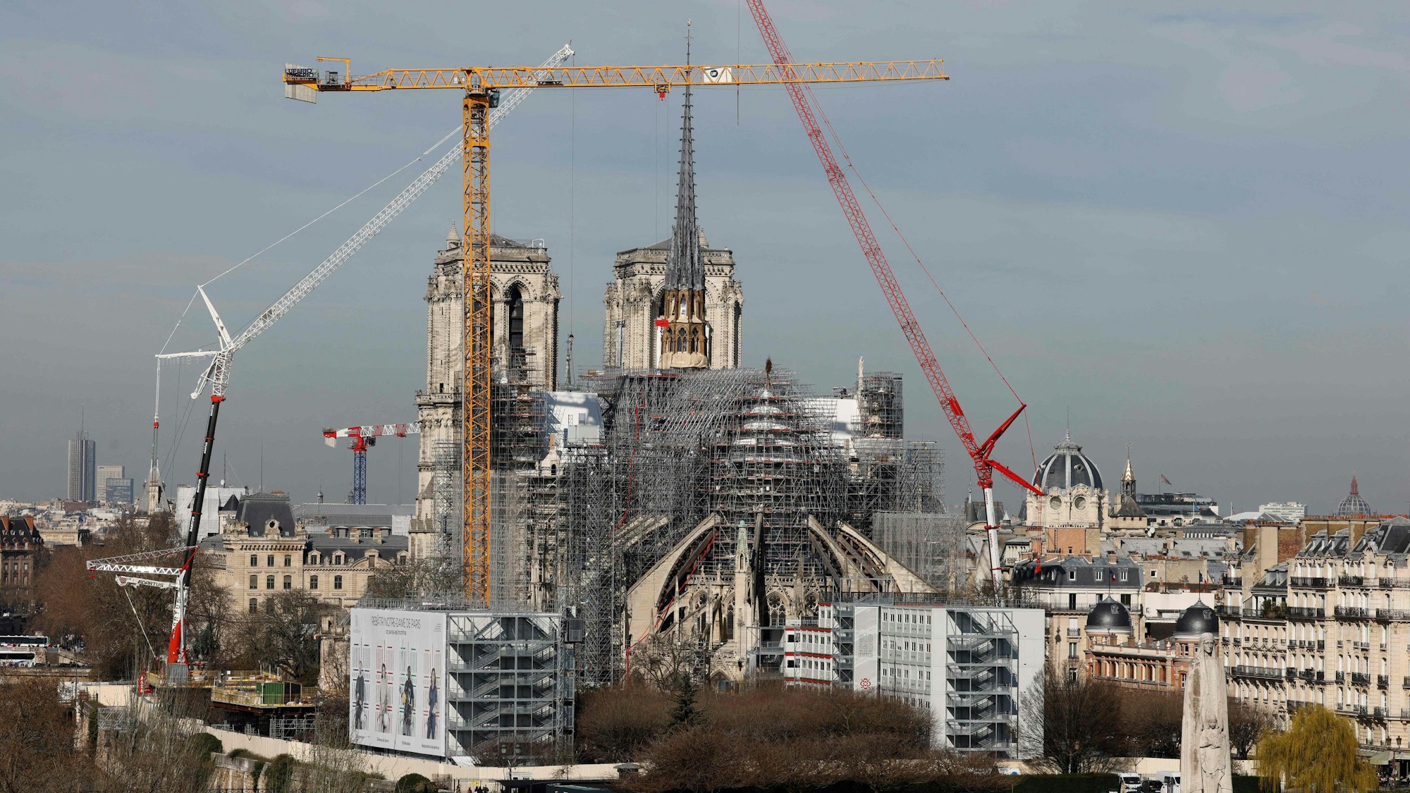 (FILES) This photograph taken on March 14, 2024, shows a view of the Notre-Dame de Paris Cathedral and its new wooden spire partially covered in lead under reconstruction with cranes and scaffholdings in Paris. A huge fire swept through the roof of the famed Notre-Dame Cathedral in central Paris on April 15, 2019, and five years later, the reconstruction advances in its final stages before the reopening planned for the end of the year. (Photo by Ludovic MARIN / AFP)