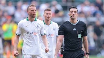Schiedsrichter bei einem Spiel von Borussia Mönchengladbach. Im Hintergrund Marvin Friedrich und Nico Elvedi.