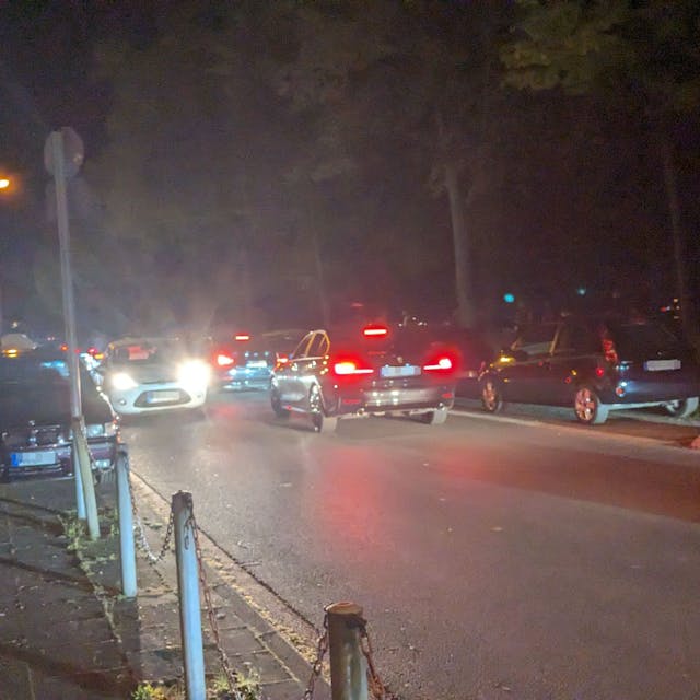 Autos fahren die Alfred-Schütte-Allee in der Nacht entlang.