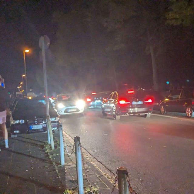 Autos fahren die Alfred-Schütte-Allee in der Nacht entlang.
