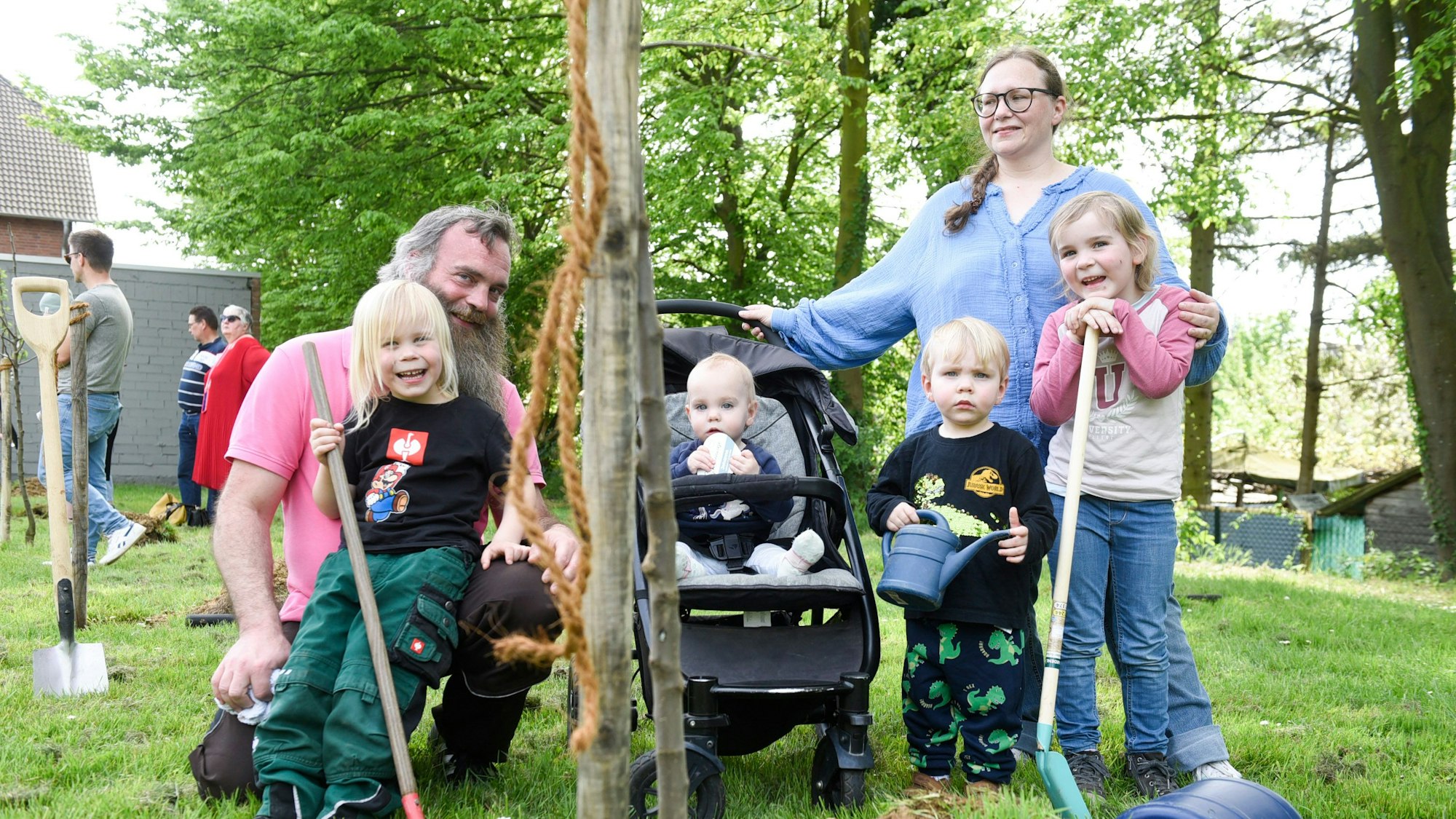 Eine Familie mit vier Kindern pflanzt einen Baum.