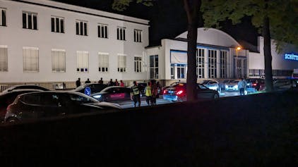Die Alfred-Schütte-Allee bei Nacht. Das Ordnungsamt patrouilliert auf der Allee, am Straßenrand stehen die Autos der Raser- und Poserszene Kölns. Foto von Florian Holler