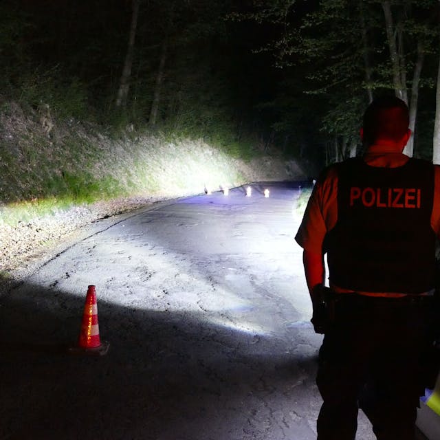 Ein Polizist blickt im Dunkeln auf einen abgesperrten Bereich.