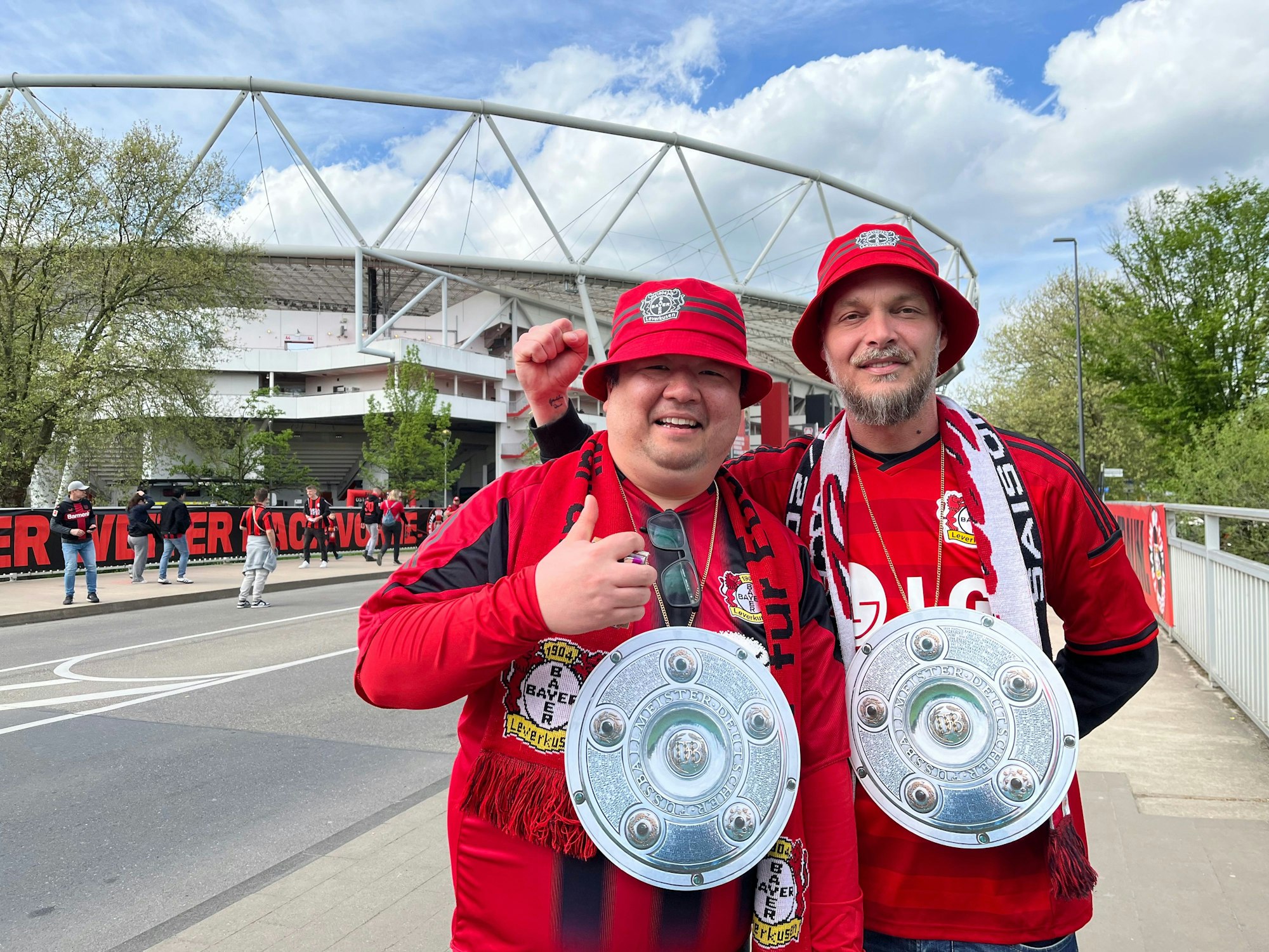 Die Bayer-Fans Ji und Elmar stehen am Stadion in Leverkusen und sind bestens auf den Erfolgsfall vorbereitet.