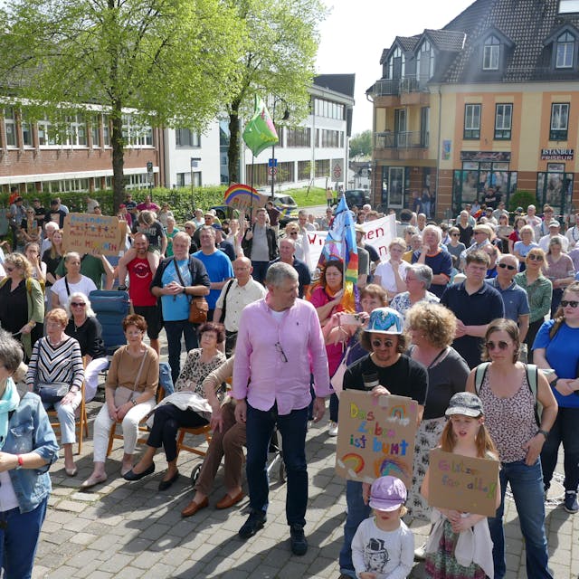 Menschen, zum Teil mit bunt beschriebenen Pappschildern, stehen auf dem Marktplatz in Neunkirchen-Seelscheid.