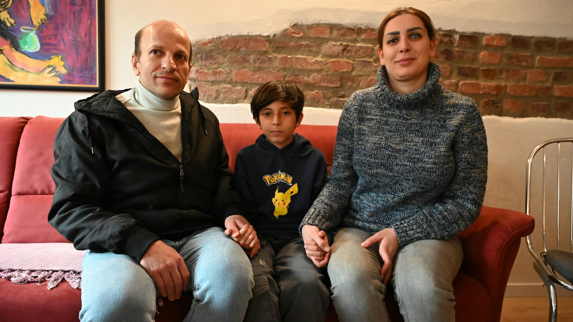 Das Bild zeigt die iranische Familie. Sie sitzen auf einem roten Sofa.