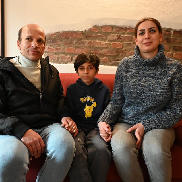 Das Bild zeigt die iranische Familie. Sie sitzen auf einem roten Sofa.