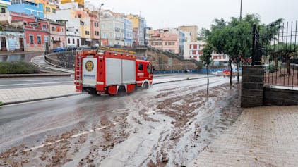 Ein Feuerwehrauto fährt nach Regen eine schlammige Straße entlang.