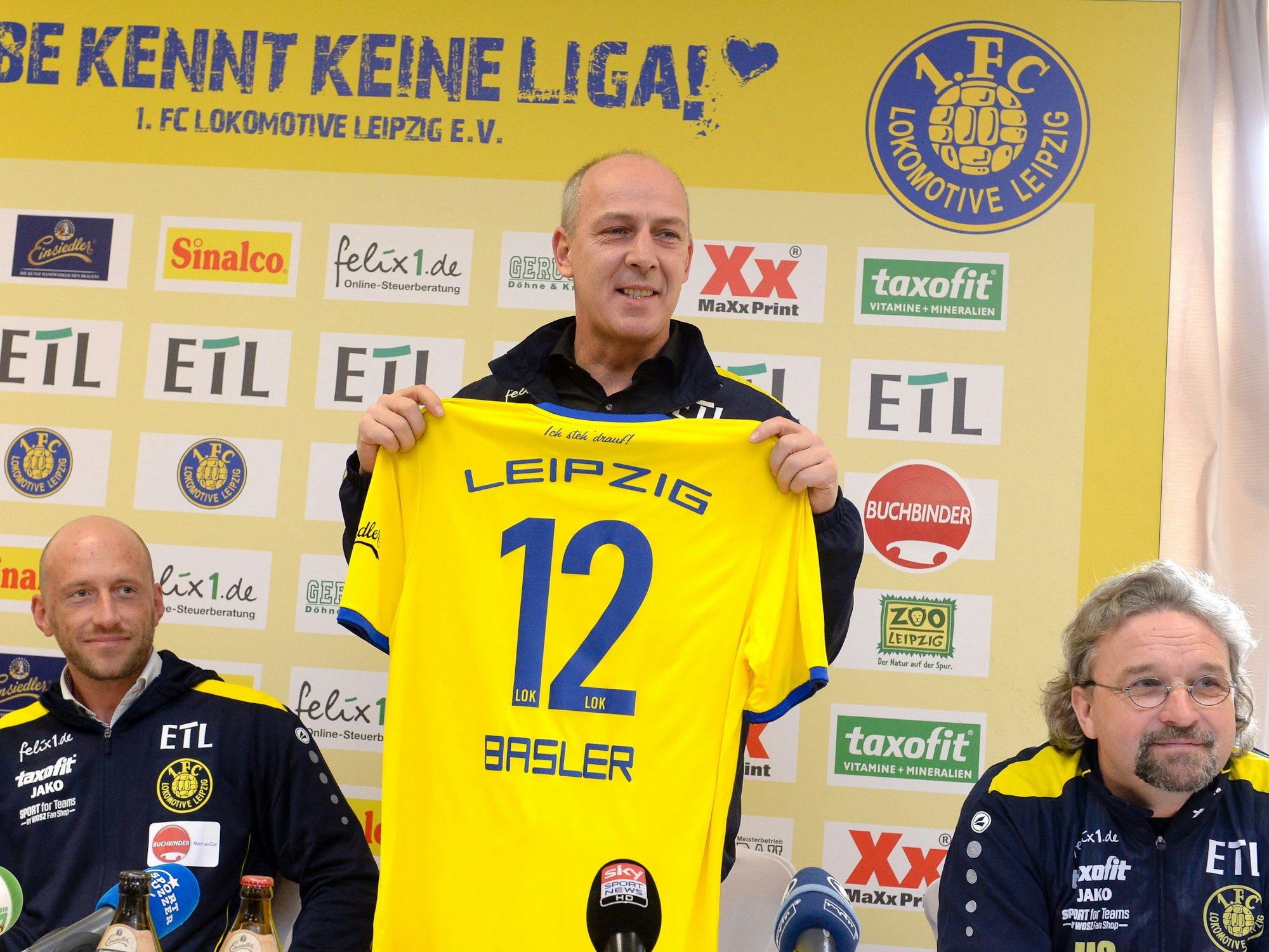 Mario Basler hält das Vereinstrikot des 1. FC Lokomotive Leipzig auf einer Pressekonferenz hoch