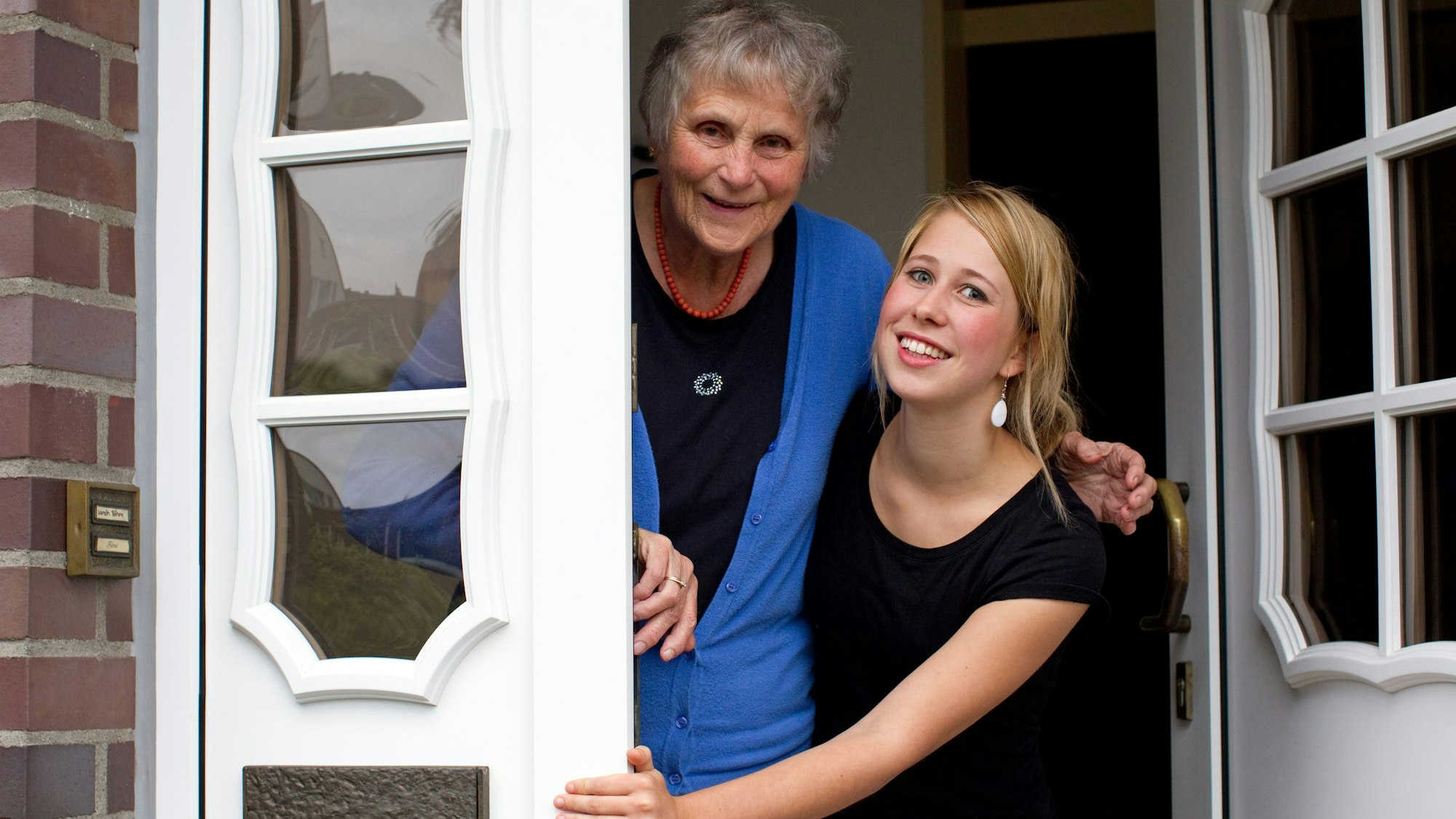 Eine Seniorin und eine bei ihr lebende Studentin stehen an einer Hauseingangstür  (Symbolbild).