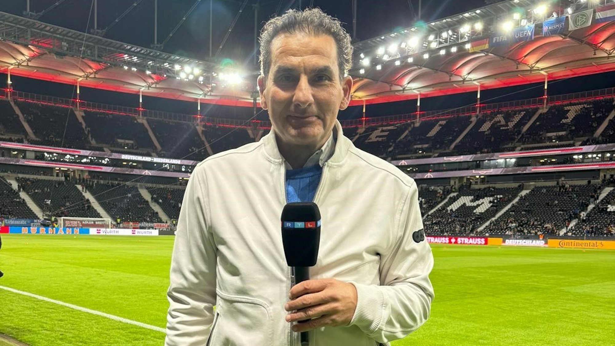 Das Foto zeigt Felix Görner mit einem Mikrofon in einem Fußballstadion.