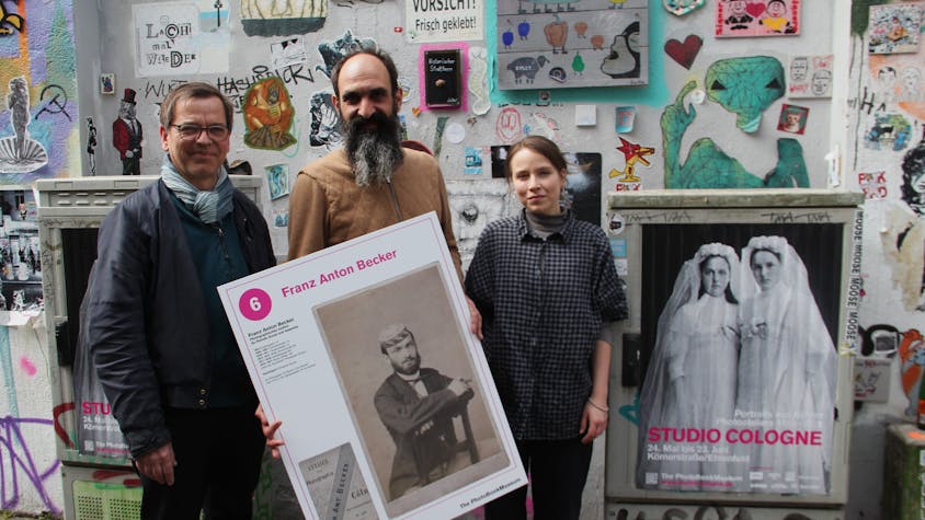 Markus Schaden, Frederic Lezmi und Leonie Serbo (v. l.) halten ein Porträt von Franz Anton Becker aus einem Kölner Photoatelier des 19. und 20. Jahrhunderts.