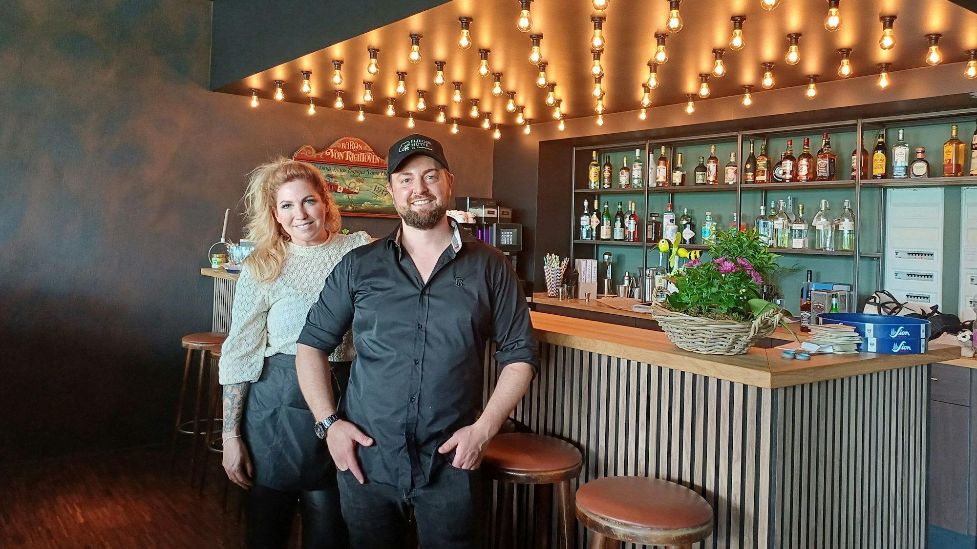 Eine Frau und ein Mann stehen in einem Restaurant an einem Tresen.