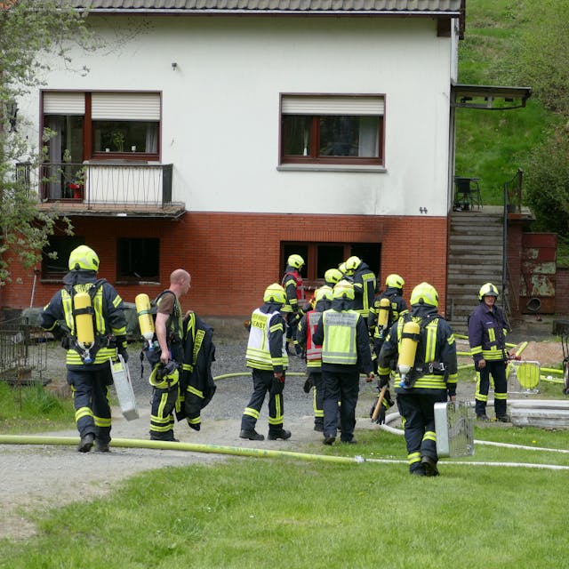 Feuerwehrleute stehen vor dem betroffenen Haus.