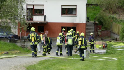 Feuerwehrleute stehen vor dem betroffenen Haus.