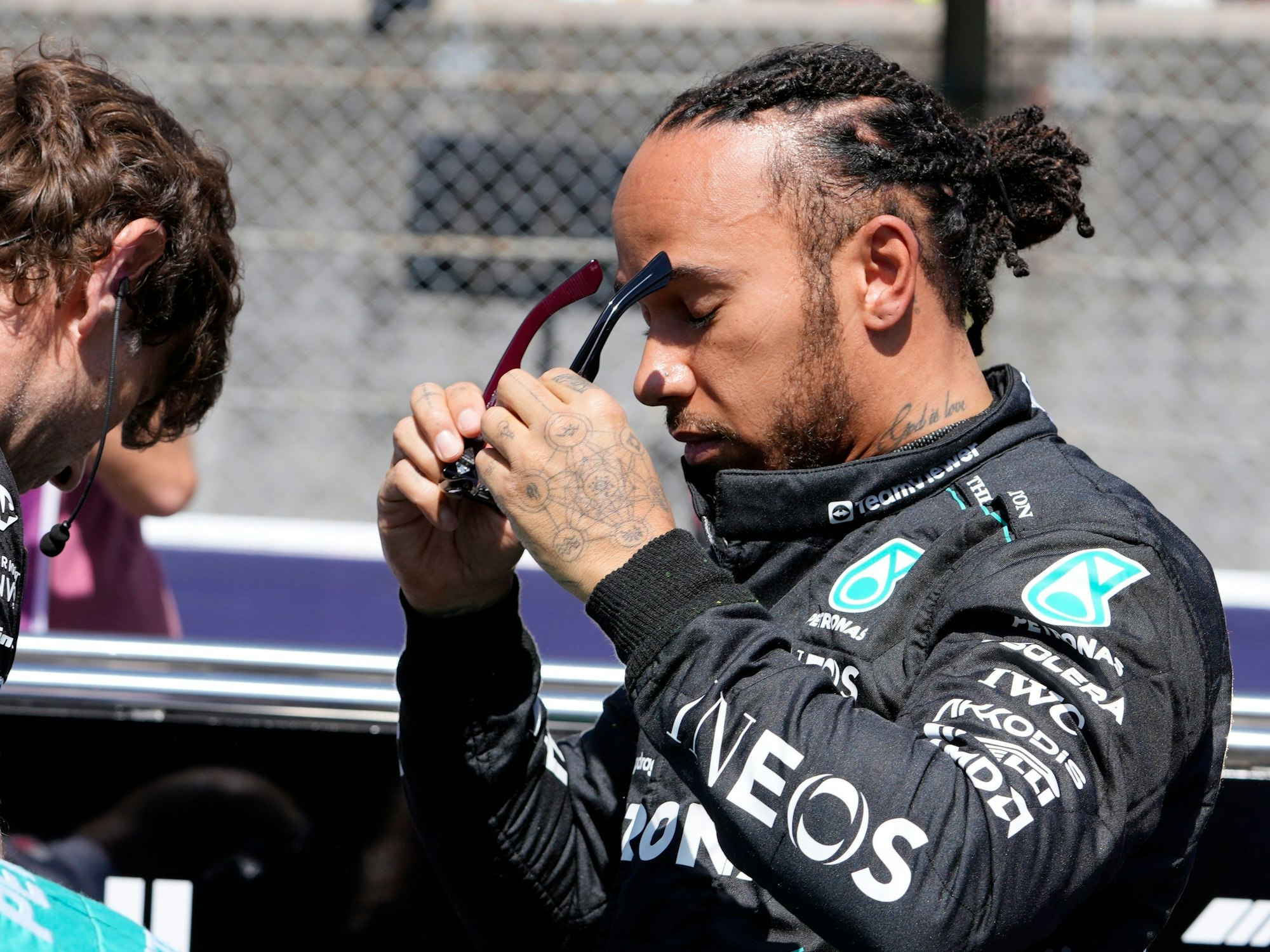 Lewis Hamilton setzt sich eine Sonnenbrille auf.
