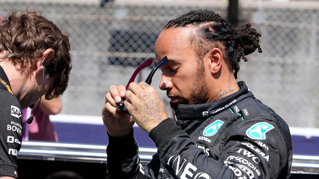 Lewis Hamilton setzt sich eine Sonnenbrille auf.