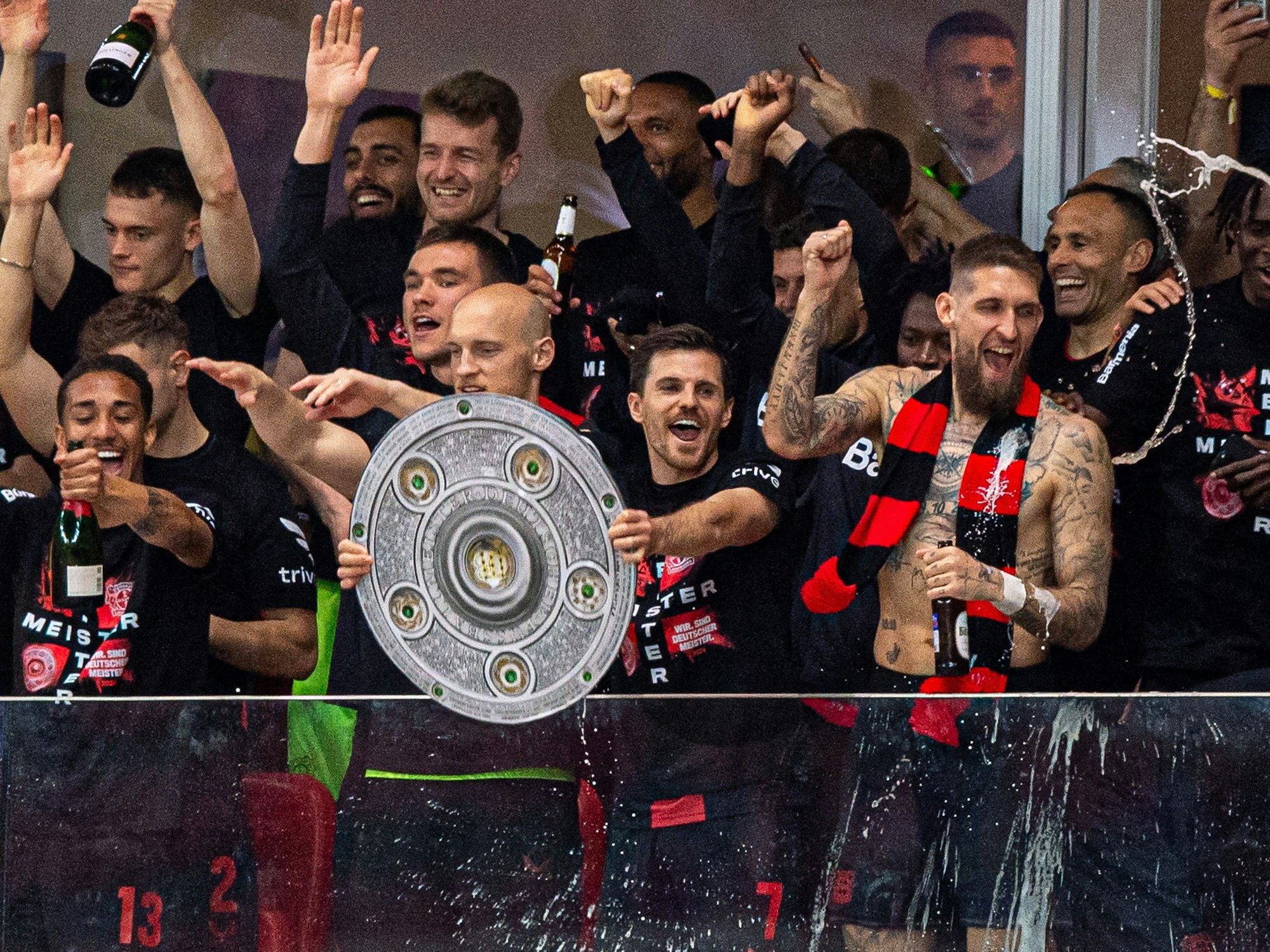 Die Mannschaft von Leverkusen präsentiert sich in einer Loge mit einer Pappe der Meisterschale