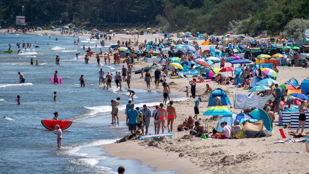 Zahlreiche Menschen sind bei sonnigem Wetter am Strand der Insel Usedom unterwegs.