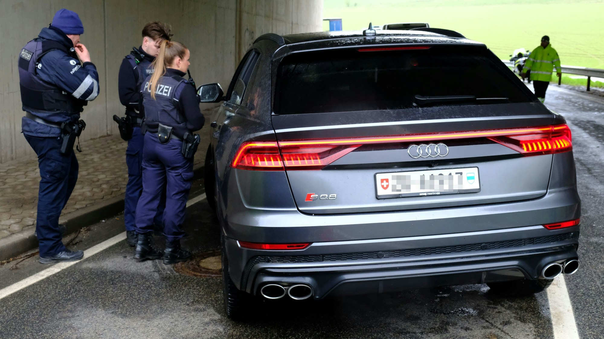 Drei Polizeibeamte stehen an einem Audi-SUV mit Schweizer Kennzeichen.