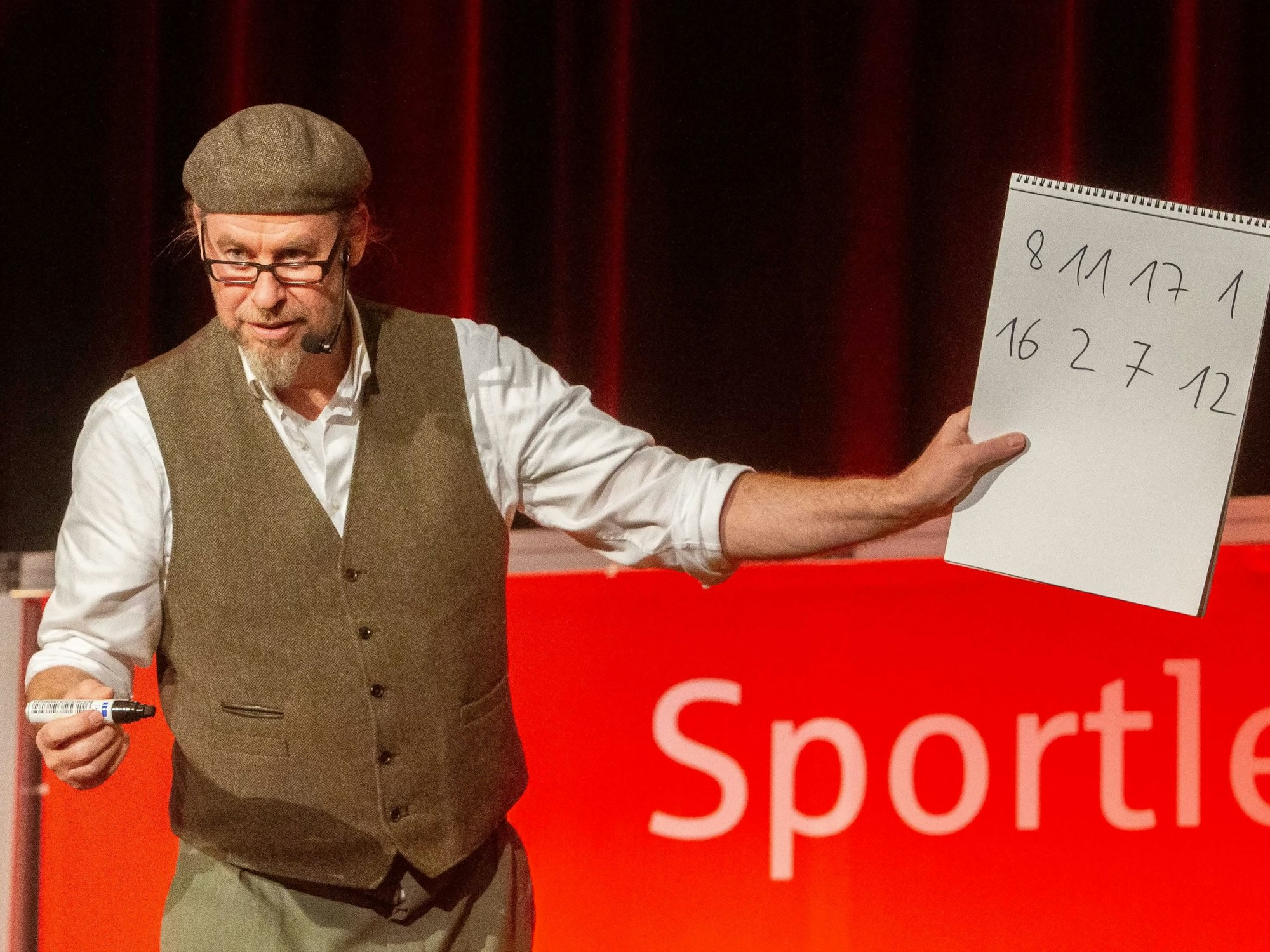 Zauberkünstler Andreas Monien hält ein Blatt mit Zahlen in der Hand.