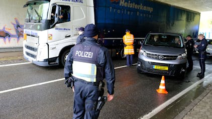 Beamte aus Deutschland und Belgien an einer gemeinsamen Kontrollstelle der Polizei an der B51 bei Dahlem-Baasem. Ein Lastwagen fährt vorbei, Polizisten stehen an einem Kleinbus mit luxemburgischen Kennzeichen.