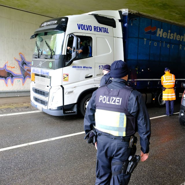 Beamte aus Deutschland und Belgien an einer gemeinsamen Kontrollstelle der Polizei an der B51 bei Dahlem-Baasem. Ein Lastwagen fährt vorbei, Polizisten stehen an einem Kleinbus mit luxemburgischen Kennzeichen.