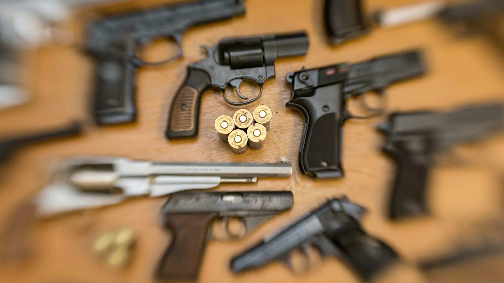 Pistolen und Revolver und Munition liegen auf einem Tisch.