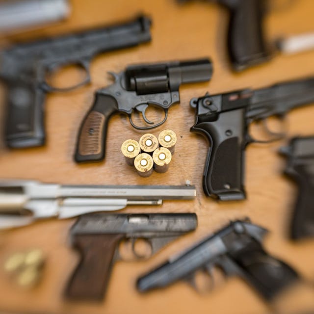 Pistolen und Revolver und Munition liegen auf einem Tisch.