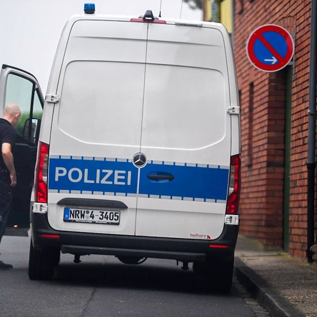 Ein Beamter steht in der Nähe des Tatorts neben einem Polizeifahrzeug.