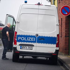 Ein Beamter steht in der Nähe des Tatorts neben einem Polizeifahrzeug.
