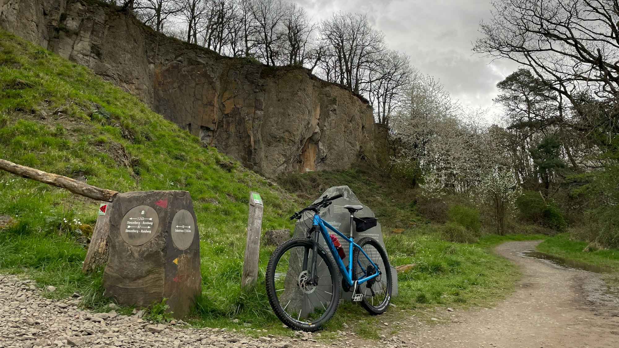 Ein Fahrrad lehnt an einem Hinweisschild, im HIntergrund der Stenzelberg