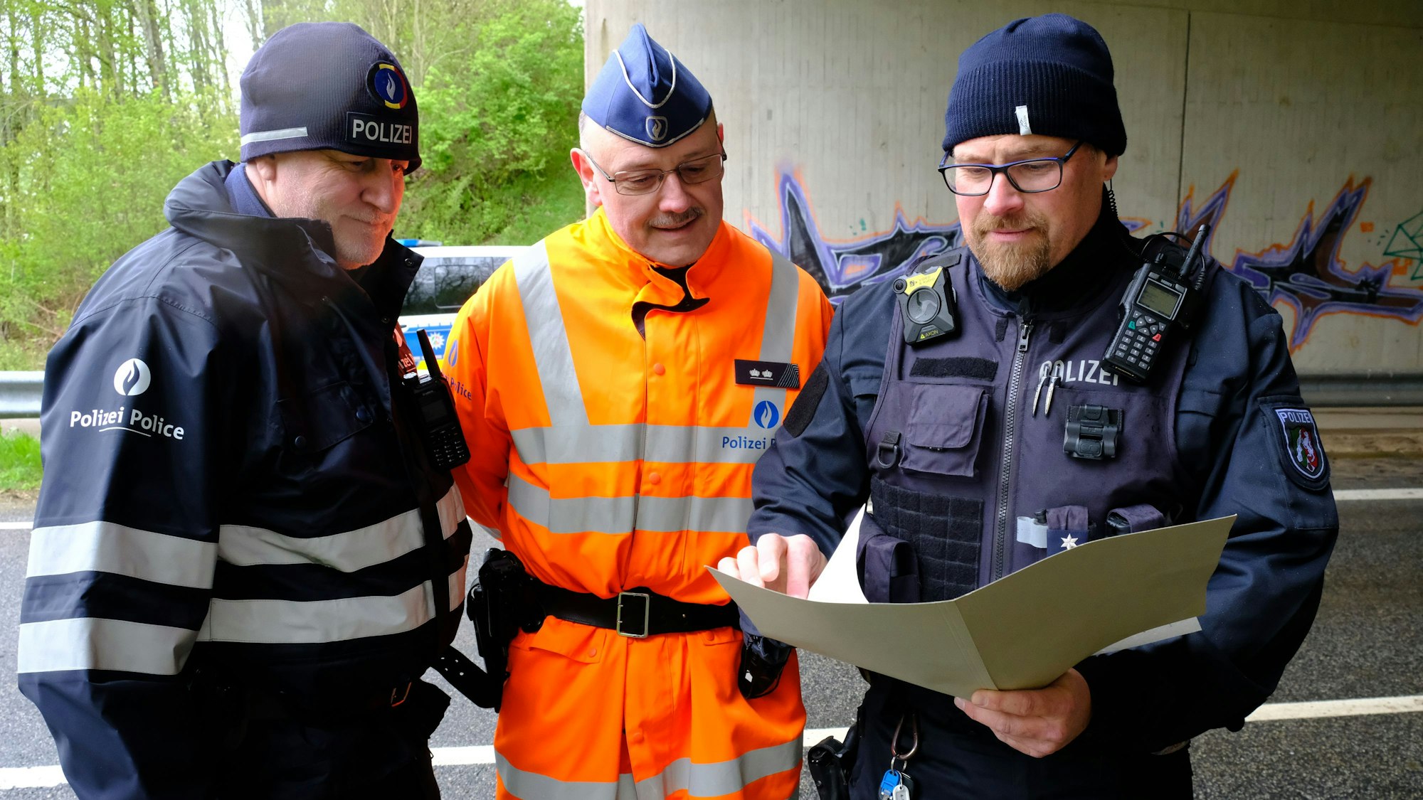 Polizei-Einsatzleiter Volker Braun (r.) steht mit seinen belgischen Kollegen Christoph Kever (M.) und Patrick Fleuster an der Kontrollstelle bei Dahlem.