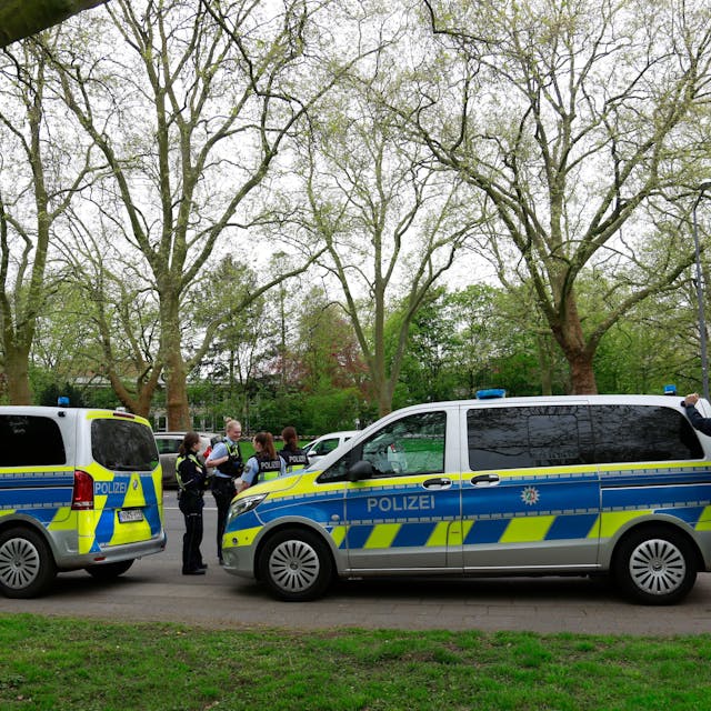 Polizisten und Streifenwagen stehen am Freitag, 12.04.2024, vor dem Gymnasium Kreuzgasse an der Vogelsanger Straße.&nbsp;