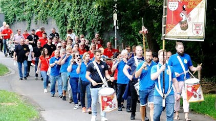 Menschen, die im Spielmannszug der Freiwilligen Feuerwehr Köln-Porz-Langel aktiv sind, ziehen mit ihren Instrumenten durch Porz.