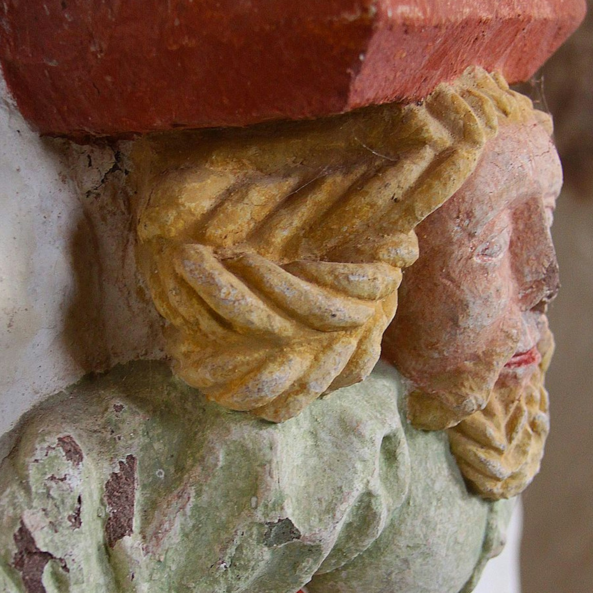 Das Bild zeigt den Pfeilerbündelträger. Die dargestellte Person hat gelbe Haare, ein rosafarbenes Gesicht und grüne Kleidung.