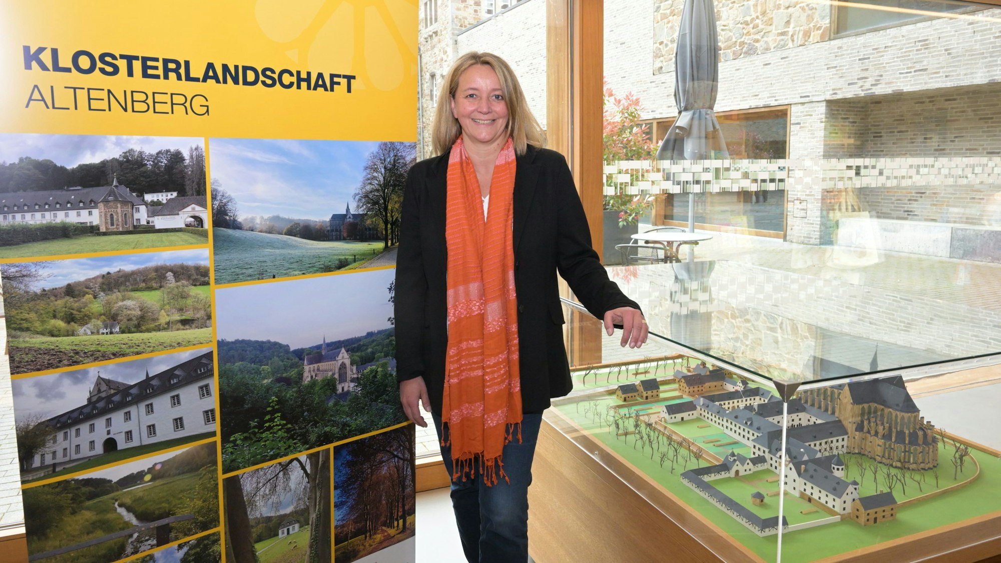 Xandra Wildung vor einer Leinwand mit Fotos aus Altenberg. Neben ihr ein Modell der ehemaligen Klosteranlage.