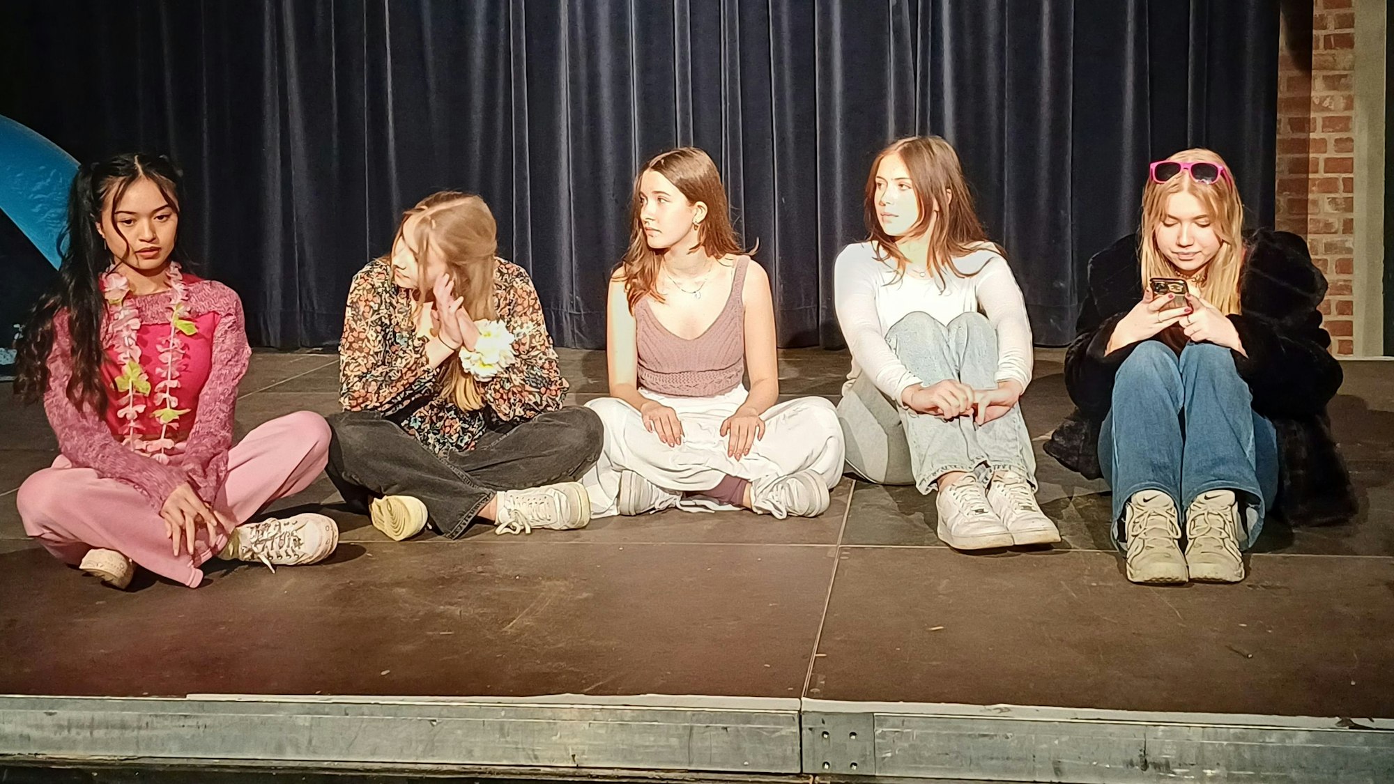 Fünf Schülerinnen sitzen auf einer Bühne.
