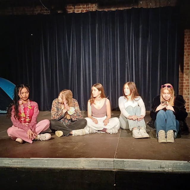 Fünf Schülerinnen sitzen auf einer Bühne.