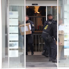 Solingen: Polizeibeamte tragen in Kartons sichergestelltes Material aus einem Gebäude.