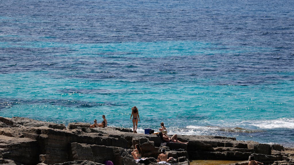 Menschen entspannen sich am Felsenstrand von Maioris an der Südostküste Mallorcas.