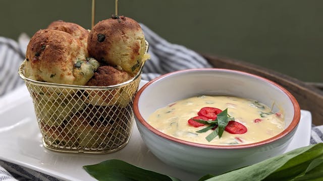 Kartoffel-Bärlauch-Bällchen stehen in einem Körbchen neben einer Schüssel mit Sauce Hollandaise-Dip.