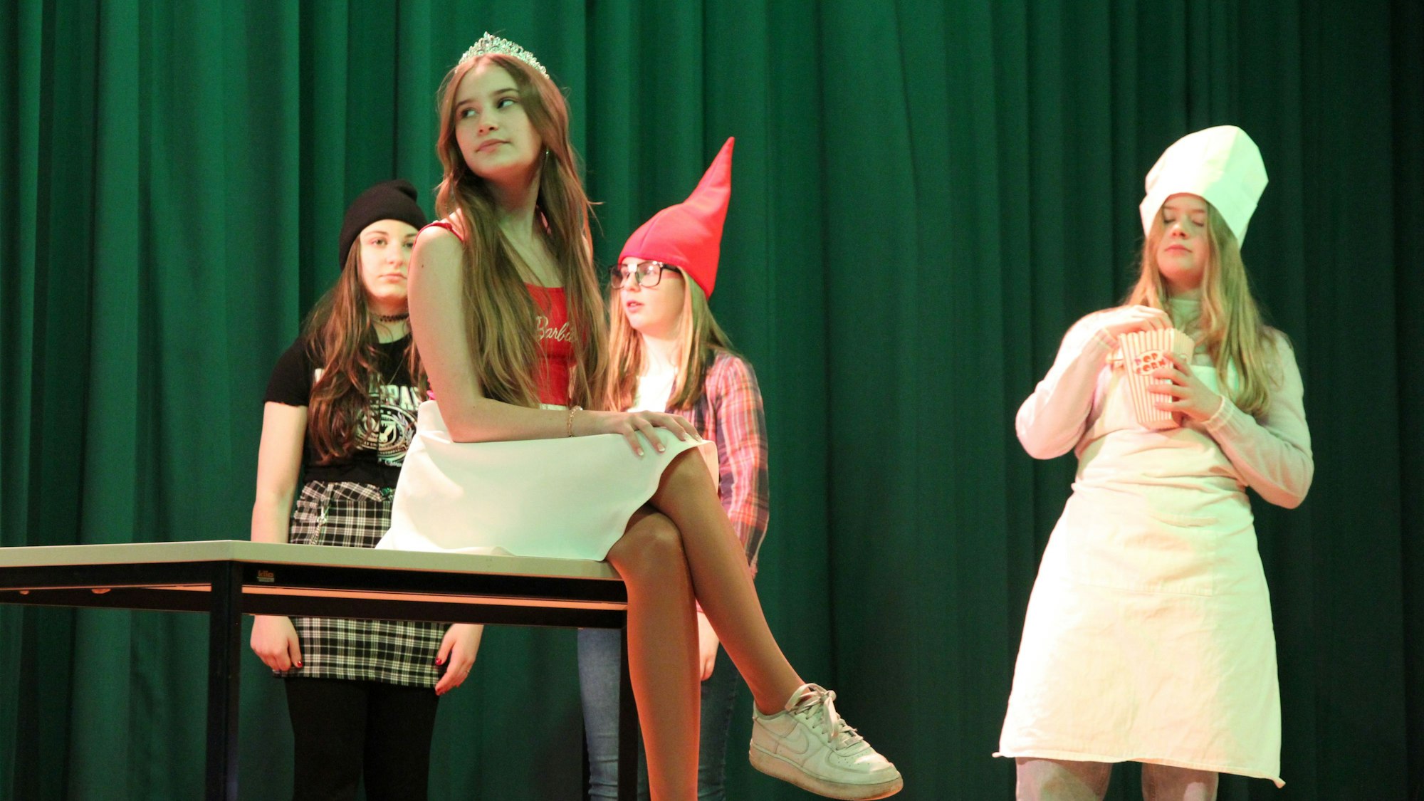 Vier Schülerinnen bei einer Theateraufführung, kostümiert als Schneewittchen mit Zwergen