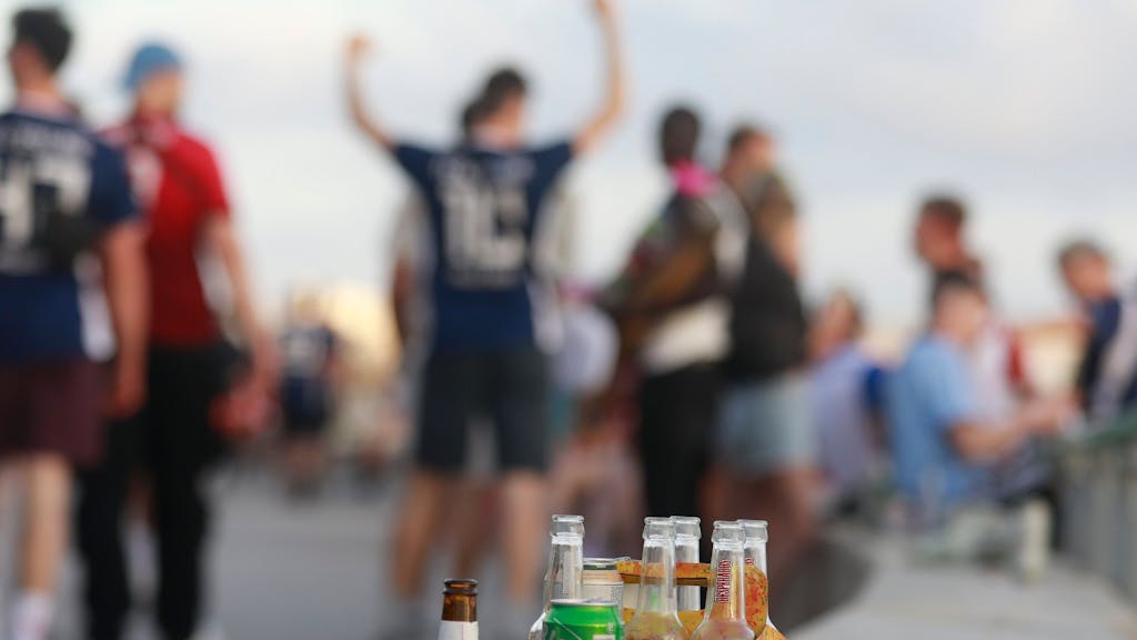 Menschen haben sich am Abend an der Promenade am Strand von Arenal versammelt. Auf einer Balustrade stehen mehrere leere Flachen alkoholischer Getränke (Symbolfoto).
