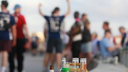 Menschen haben sich am Abend an der Promenade am Strand von Arenal versammelt. Auf einer Balustrade stehen mehrere leere Flachen alkoholischer Getränke (Symbolfoto).