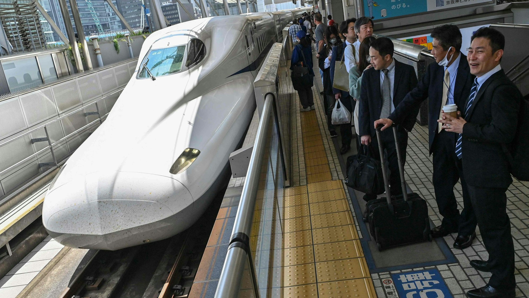 Passagiere warten am Gleis auf den Hochgeschwindigkeitszug Shinkansen.