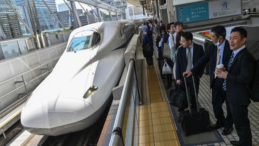 Passagiere warten am Gleis auf den Hochgeschwindigkeitszug Shinkansen.